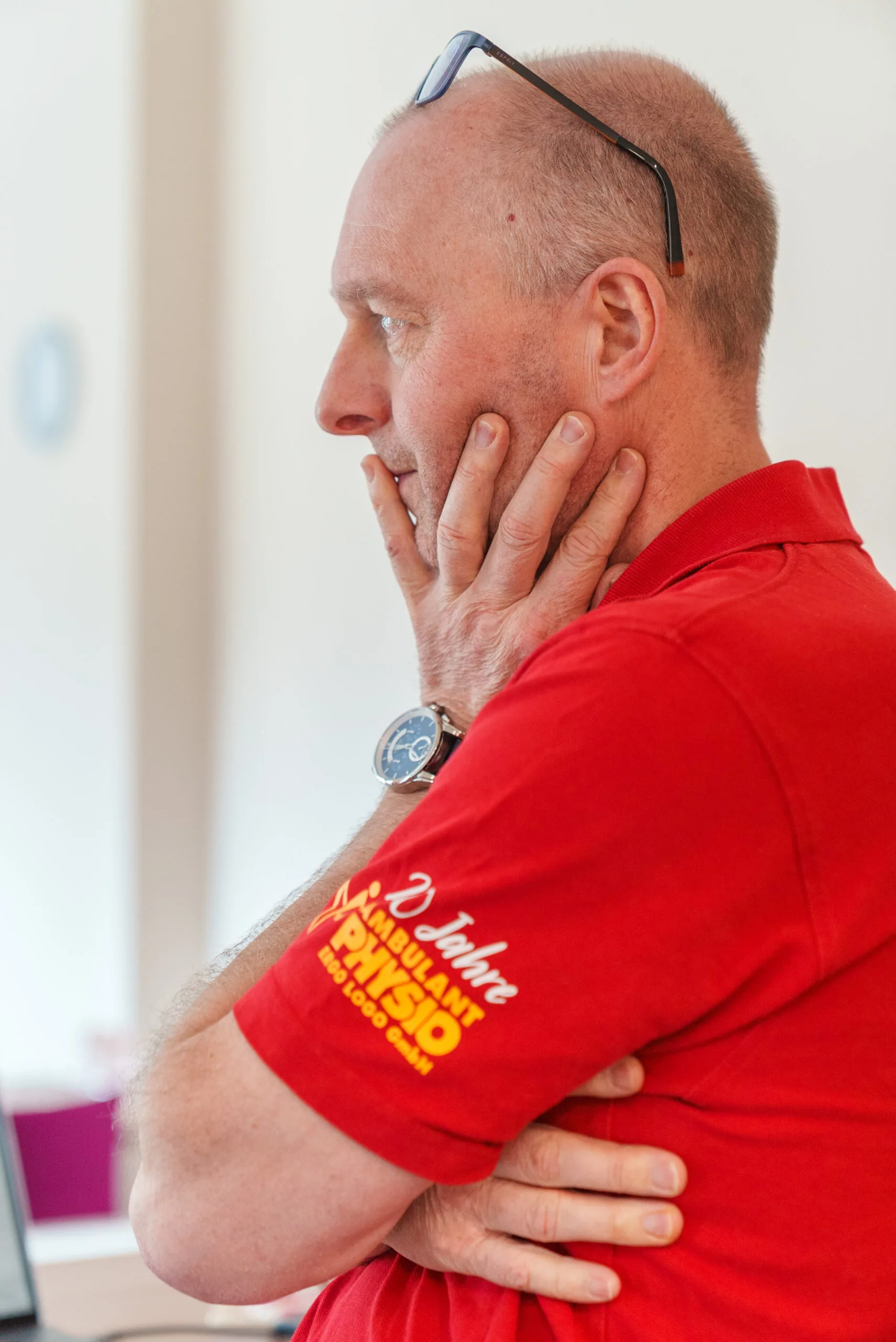 Torsten „TOHO“ Erler im roten Poloshirt, nachdenklich mit der Hand am Kinn, im hellen Büro